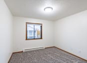 Thumbnail 18 of 23 - an empty living room with carpet and a window. Fargo, ND Flagstone Apartments