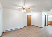 Thumbnail 15 of 23 - an empty living room with a ceiling fan and a kitchen. Fargo, ND Flagstone Apartments