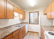 Thumbnail 14 of 23 - an empty kitchen with wooden cabinets and granite counter tops. Fargo, ND Flagstone Apartments