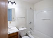 Thumbnail 6 of 7 - a bathroom with a shower toilet and sink and a mirror. Fargo, ND Forest Avenue Apartments