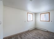 Thumbnail 3 of 7 - the living room of an empty house with carpet and two windows. Fargo, ND Forest Avenue Apartments