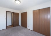 Thumbnail 10 of 13 - an empty room with three doors and a door to a closet. Fargo, ND Hartford Apartments