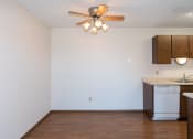 Thumbnail 9 of 13 - an empty living room with a ceiling fan and a kitchen. Fargo, ND Hartford Apartments