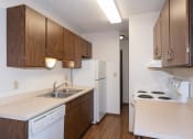 Thumbnail 8 of 13 - an empty kitchen with white appliances and wooden cabinets. Fargo, ND Hartford Apartments
