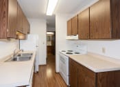 Thumbnail 7 of 13 - an empty kitchen with white appliances and wooden cabinets. Fargo, ND Hartford Apartments