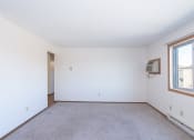 Thumbnail 6 of 13 - the living room of an apartment with carpet and a window. Fargo, ND Hartford Apartments