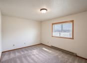 Thumbnail 9 of 13 - the living room of an empty house with a window and a carpet. Fargo, ND Hunters Run 2 Apartments