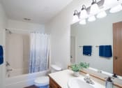 Thumbnail 13 of 14 - a bathroom with a shower toilet and sink and a mirror. Fargo, ND Kentwood Manor Apartments