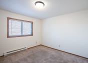 Thumbnail 9 of 14 - the living room of an empty house with carpet and a window. Fargo, ND Kentwood Manor Apartments