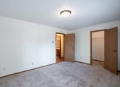 Thumbnail 11 of 14 - a bedroom with a door to a hallway and a closet. Fargo, ND Kentwood Manor Apartments