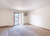 Thumbnail 4 of 14 - an empty living room with a door to a balcony. Fargo, ND Kentwood Manor Apartments