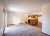 Thumbnail 5 of 14 - an empty living room with a kitchen with white appliances. Fargo, ND Kentwood Manor Apartments