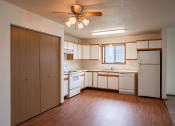 Thumbnail 20 of 49 - an empty kitchen with white appliances and wooden floors and a ceiling fan. West Fargo, ND Lake Crest Apartments 21e