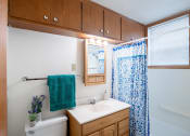 Thumbnail 9 of 11 - a bathroom with a white sink and a blue shower curtain. Fargo, ND Luxford Apartments