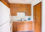 Thumbnail 4 of 11 - a small kitchen with wooden cabinets and a white refrigerator. Fargo, ND Luxford Apartments