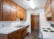Thumbnail 16 of 20 - an empty kitchen with white appliances and wooden cabinets. Fargo, ND Martha Alice Apartments | 21B