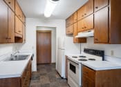 Thumbnail 17 of 20 - an empty kitchen with white appliances and wooden cabinets. Fargo, ND Martha Alice Apartments