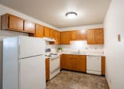 Thumbnail 20 of 26 - a small kitchen with white appliances and wooden cabinets. Fargo, ND Monticello Apartments