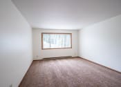 Thumbnail 9 of 26 - an empty room with carpet and a window. Fargo, ND Monticello Apartments