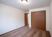 Thumbnail 16 of 26 - an empty living room with carpet and a door to a closet. Fargo, ND Monticello Apartments
