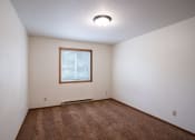 Thumbnail 17 of 26 - an empty living room with carpet and a window. Fargo, ND Monticello Apartments