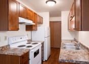Thumbnail 11 of 26 - a kitchen with white appliances and wooden cabinets and granite counter tops. Fargo, ND Monticello Apartments