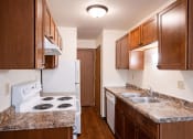 Thumbnail 12 of 26 - a kitchen with wood cabinets and white appliances and granite counter tops. Fargo, ND Monticello Apartments