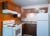 Thumbnail 10 of 15 - an empty kitchen with white appliances and wooden cabinets. Fargo, ND Morningside Apartments