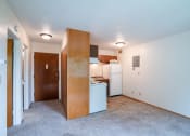 Thumbnail 9 of 15 - an empty living room with a kitchen with a refrigerator and a sink. Fargo, ND Morningside Apartments