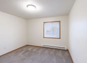 Thumbnail 24 of 31 - an empty living room with carpet and a window. Fargo, ND Oxford Apartments