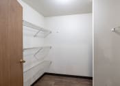 Thumbnail 26 of 31 - an empty closet with white walls and shelves and a wooden door. Fargo, ND Oxford Apartments