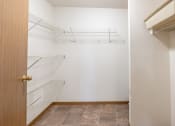 Thumbnail 17 of 31 - an empty closet with white walls and an open door to a white closet with shelves. Fargo, ND Oxford Apartments
