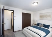 Thumbnail 6 of 22 - a bedroom with a blue and white bed and a closet. Fargo, ND Pacific Park Apartments