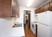 Thumbnail 9 of 22 - a kitchen with white appliances and wooden cabinets and a white refrigerator. Fargo, ND Pacific Park Apartments