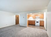 Thumbnail 13 of 22 - an empty living room with a kitchen with wood cabinets