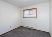 Thumbnail 11 of 18 - an empty room with a window and carpet. Fargo, ND Pacific South Apartments
