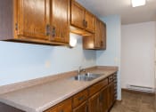 Thumbnail 8 of 18 - a kitchen with a sink and cabinets and a refrigerator. Fargo, ND Pacific South Apartments