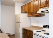 Thumbnail 7 of 18 - a kitchen with white appliances and wooden cabinets and a refrigerator. Fargo, ND Pacific South Apartments
