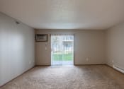 Thumbnail 12 of 16 - an empty living room with a sliding glass door to a yard