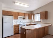 Thumbnail 7 of 19 - an empty kitchen with white appliances and wooden cabinets. Fargo, ND Rosegate Apartments