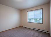 Thumbnail 33 of 61 - an empty bedroom with a large window and carpeting. Fargo, ND West Lake Apartments