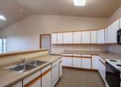 Thumbnail 32 of 61 - a kitchen with white cabinets and a living room in the background. Fargo, ND West Lake Apartments