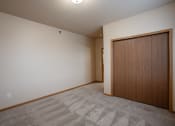 Thumbnail 46 of 61 - a bedroom of an empty apartment with a door to a closet. Fargo, ND West Lake Apartments