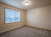 Thumbnail 45 of 61 - a bedroom with a large window and carpeted floors. Fargo, ND West Lake Apartments
