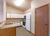 Thumbnail 42 of 61 - a kitchen with white appliances and a wooden door. Fargo, ND West Lake Apartments
