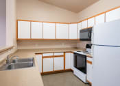 Thumbnail 41 of 61 - an empty kitchen with white cabinets and a refrigerator and sink. Fargo, ND West Lake Apartments
