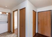 Thumbnail 23 of 25 - an empty room with three doors and a laundry room. Fargo, ND Westview Towers Apartments