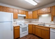 Thumbnail 19 of 25 - an empty kitchen with white appliances and wooden cabinets. Fargo, ND Westview Towers Apartments