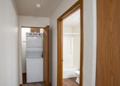 Thumbnail 22 of 25 - a hallway with a door to a room with a washer and dryer and a laundry room with a. Fargo, ND Westview Towers Apartments