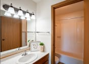 Thumbnail 15 of 25 - a bathroom with a mirror and a sink and a shower. Fargo, ND Westview Towers Apartments